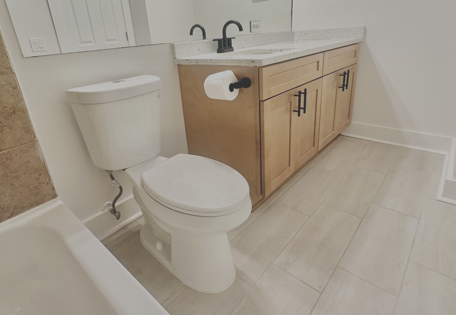 Renovated bathroom with wood vanity and matte-black hardware